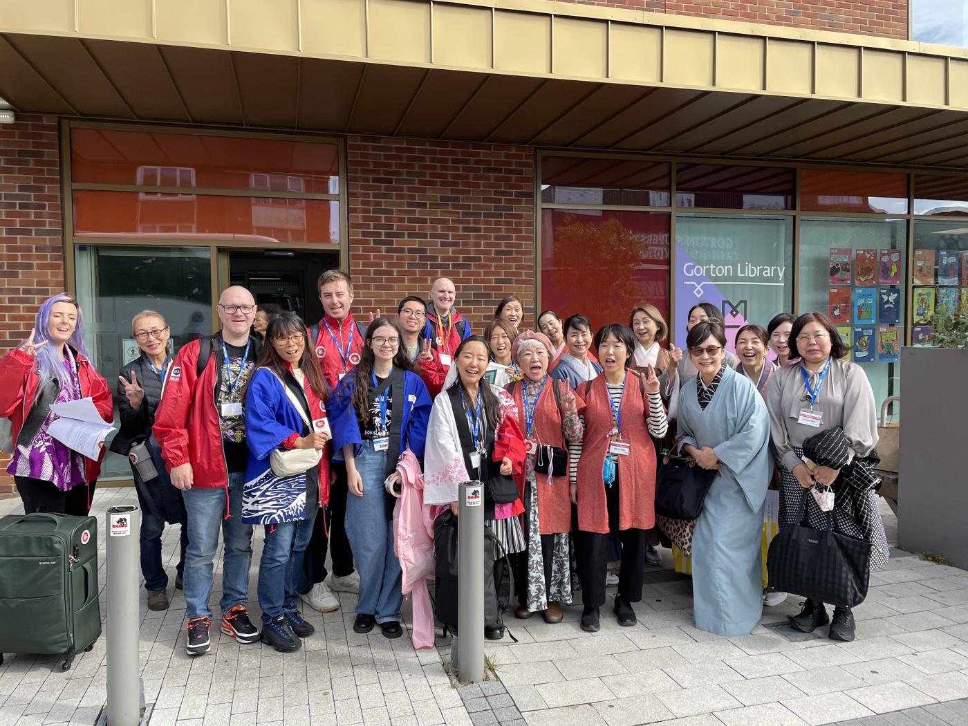 A large group of Japan Week volunteers and visitors laughing together outside Gorton Library.