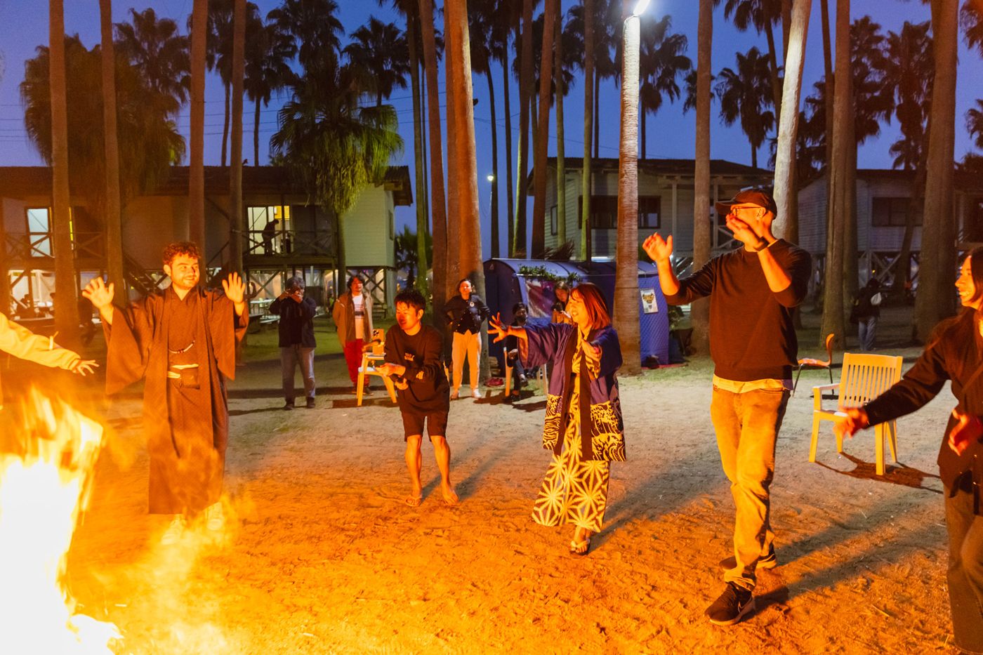 Members and international guests dancing by a bonfire at night